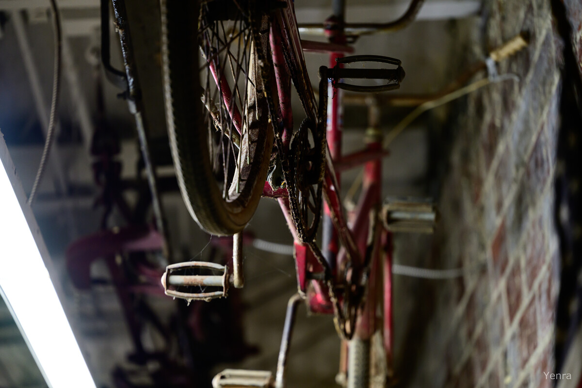 Close-up of a muddy red bicycle hanging upside down next to a brick wall