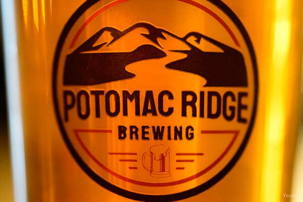 Close-up of Potomac Ridge Brewing logo on a glass bottle filled with golden liquid