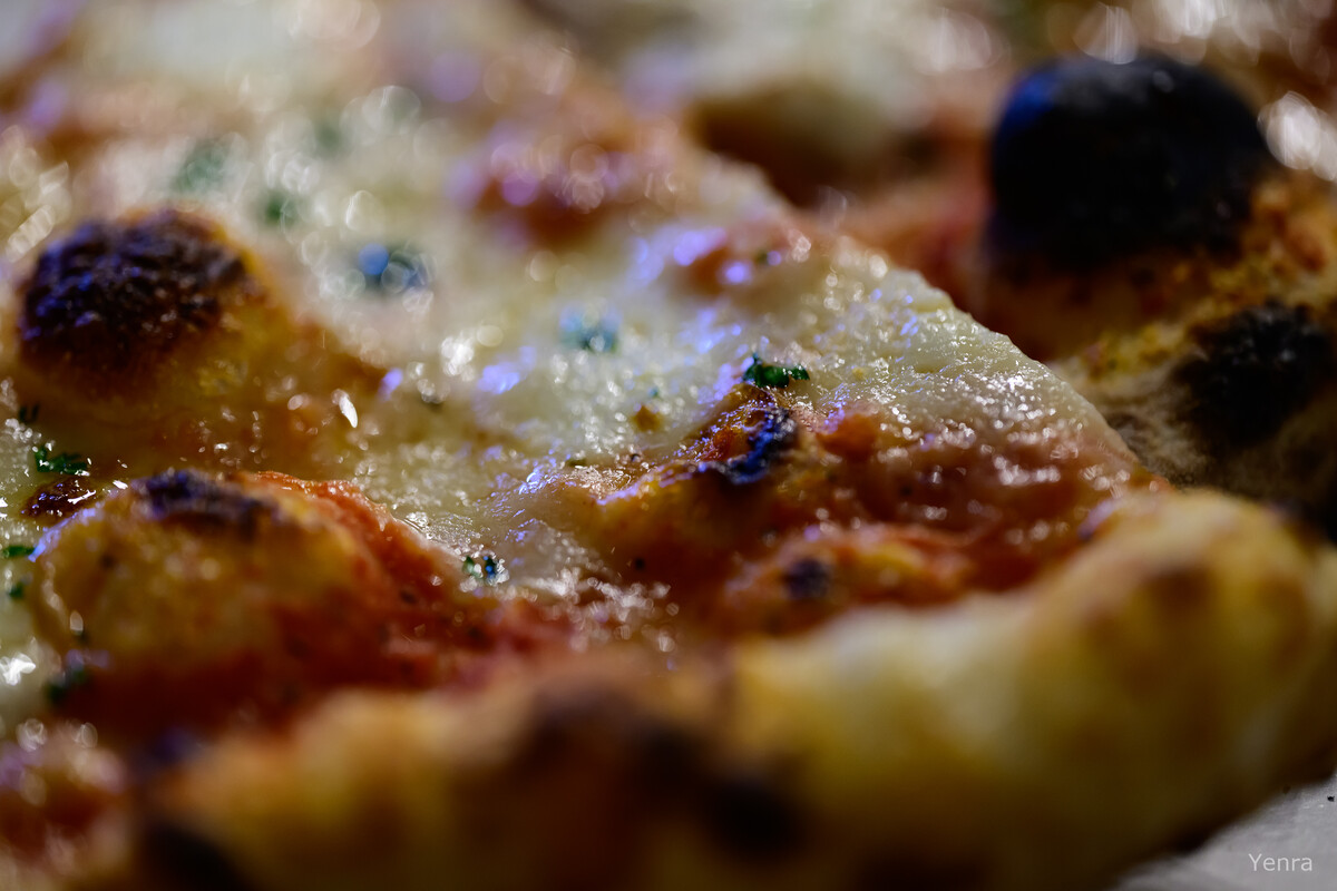 Macro photography of a pizza slice showing melted cheese, sauce, and charred toppings