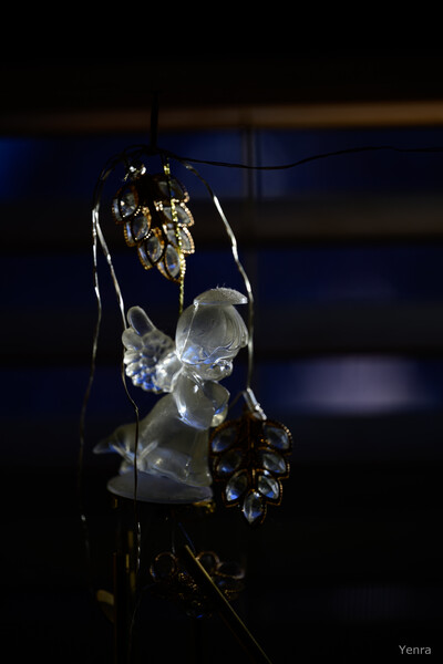 A hanging glass angel figurine surrounded by dangling crystal ornaments against a dark blue background