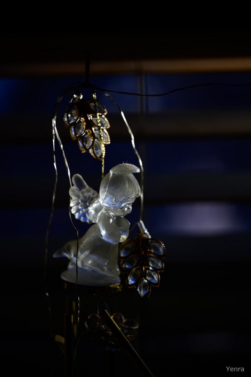 A hanging glass angel figurine surrounded by dangling crystal ornaments against a dark blue background