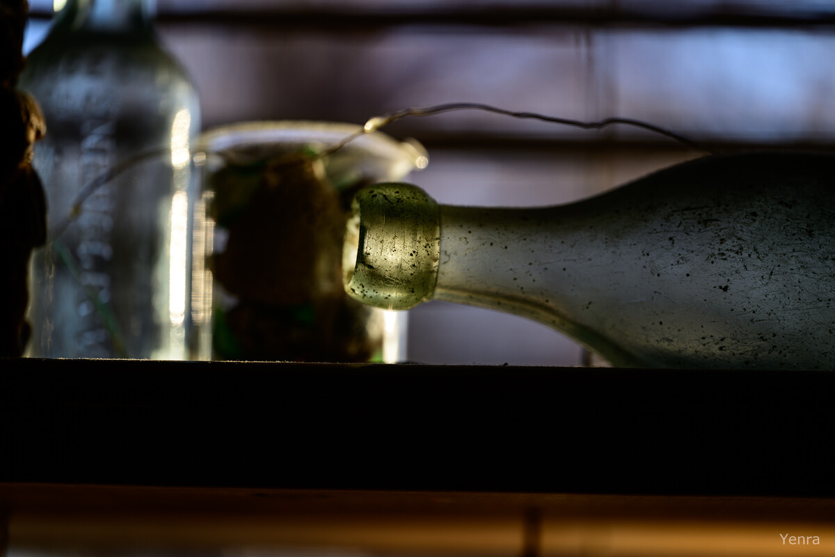 Close-up of a weathered glass bottle lying on its side with a blurred background of other containers.