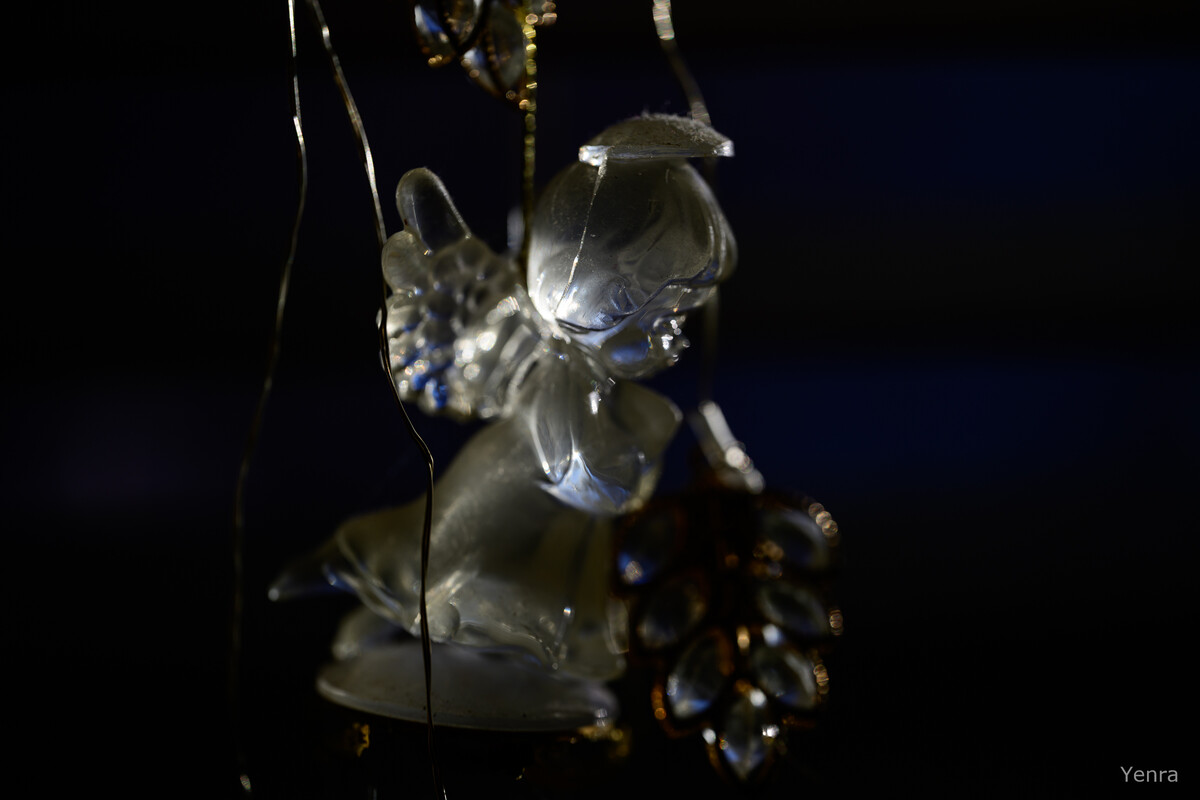 Close-up of a hanging glass angel ornament with beads against a dark background