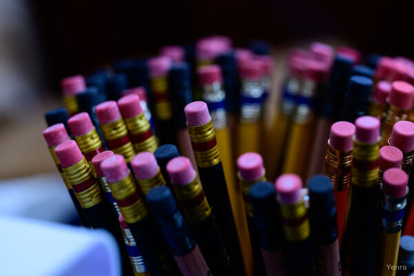 Close-up of many pencils with pink erasers arranged in a container