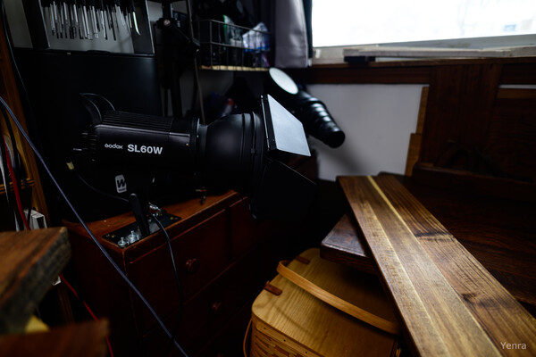 A studio lighting setup featuring a Godox SL60W flash unit next to a wooden cutting board in a room.