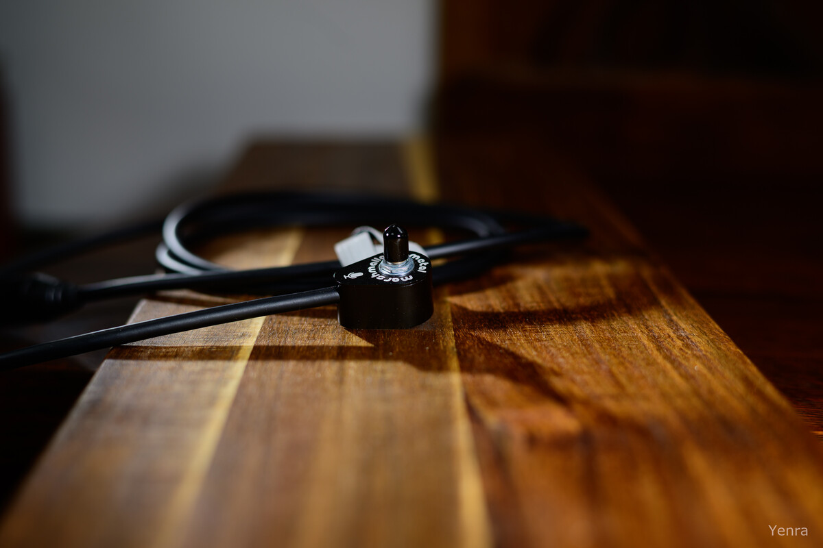 Close-up of a black contact microphone with a coiled cable resting on a wooden surface