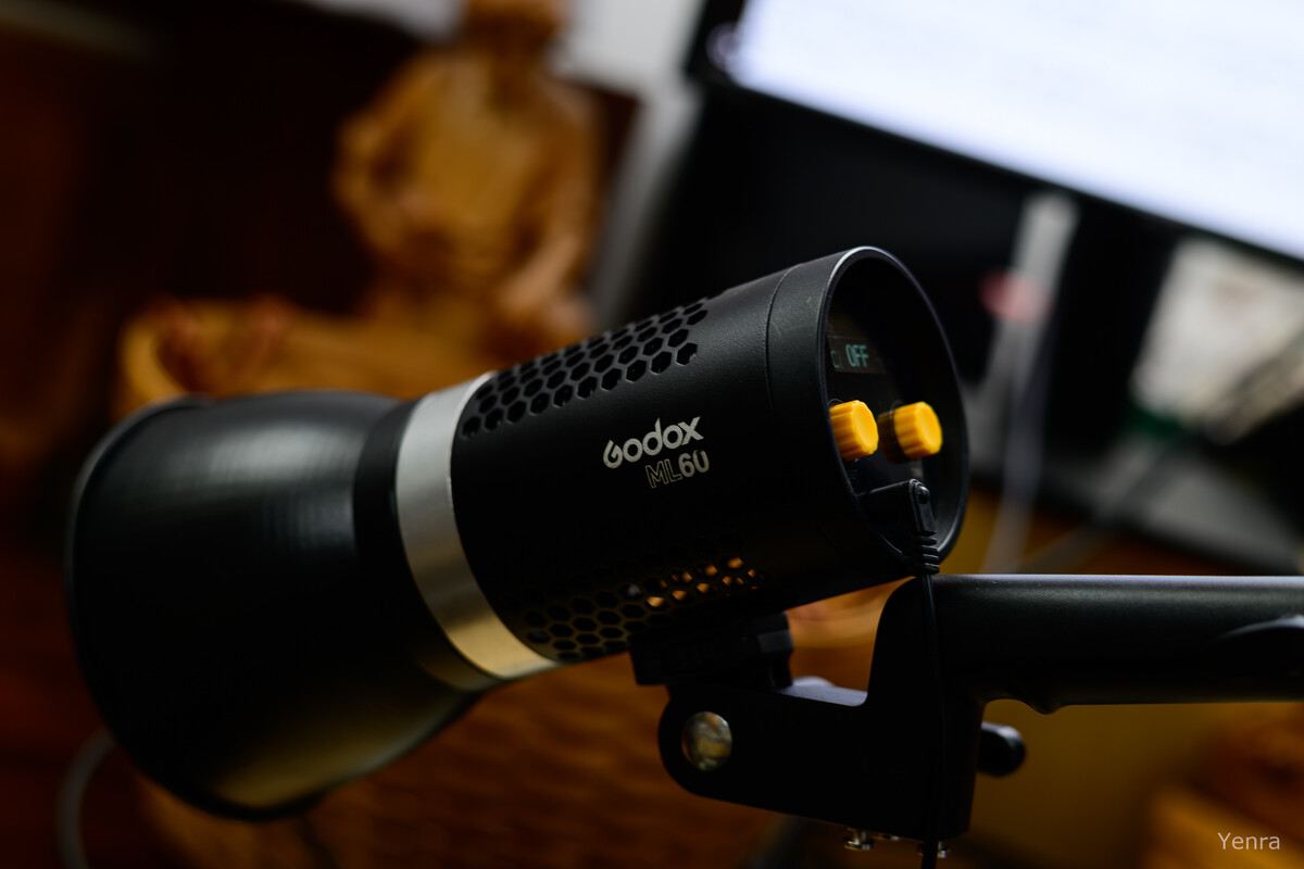Close-up of a Godox ML60 light on a stand with blurred background elements