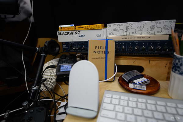 A desk with stationery, audio gear, and a keyboard