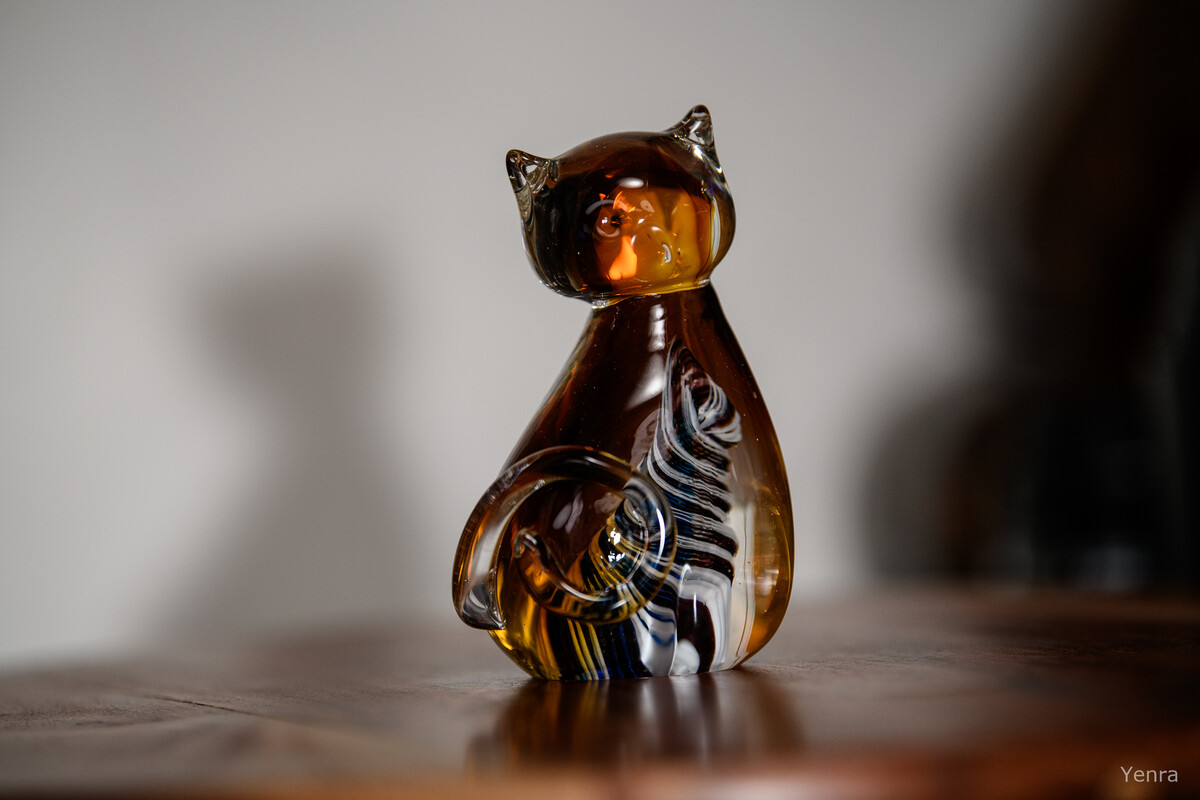Close-up of an amber glass cat figurine with colorful internal swirls sitting on wood