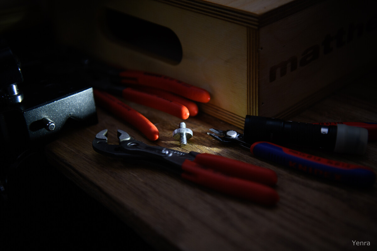 Red-handled Knipex pliers and a flashlight on a wooden surface next to a box labeled matthe