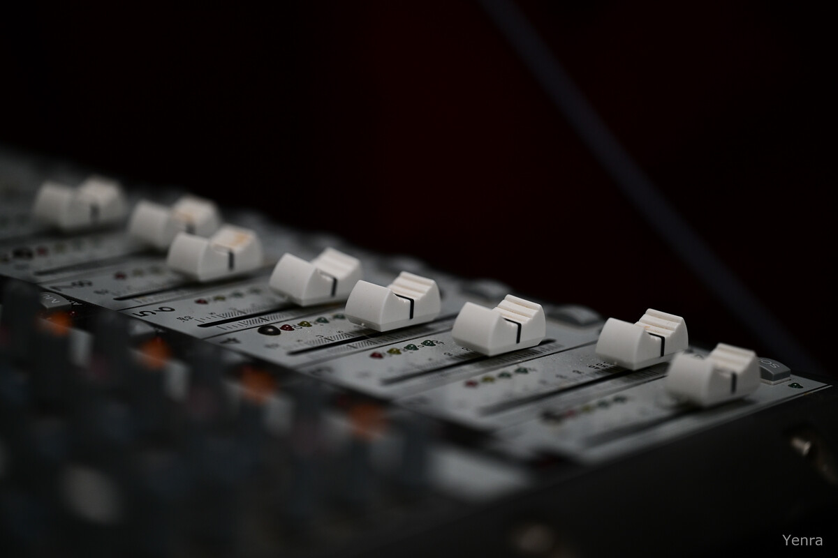 Close-up of white fader sliders on a mixing console with dark background