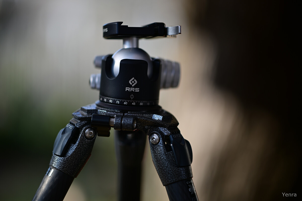 Close-up of an RRS tripod head with fluid dials and a ball mount against a blurred background