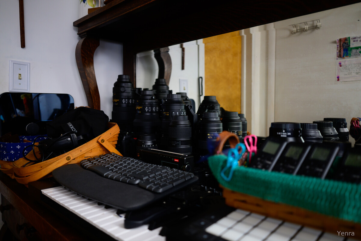 Photography equipment including lenses and keyboards on a desk with mirror reflections