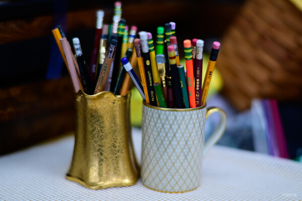 Two containers holding an assortment of colored pencils on a white textured surface