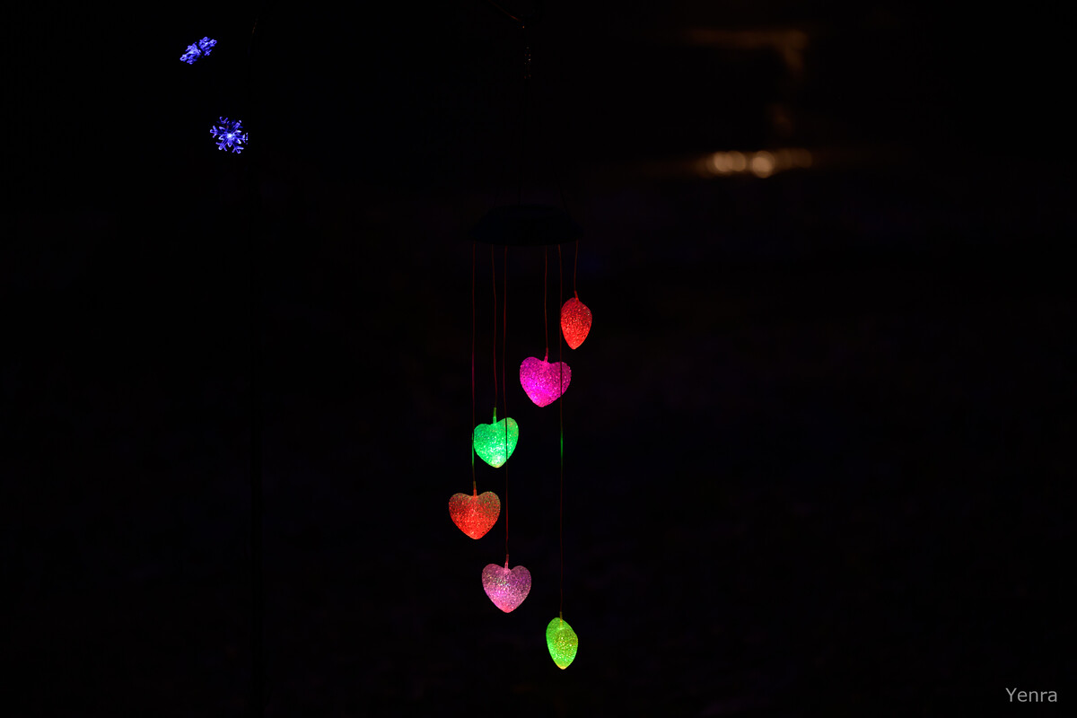 Glowing heart-shaped lights hanging vertically against a dark background with blue floral lights above