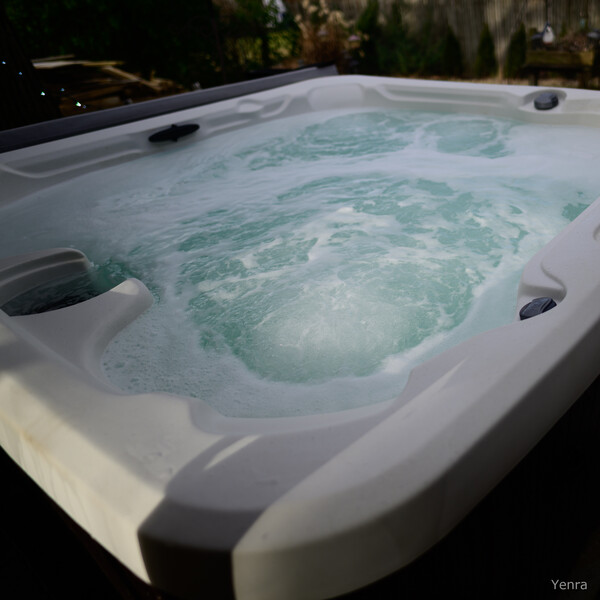 High angle shot of a bubbling white hot tub with swirling water in a backyard setting