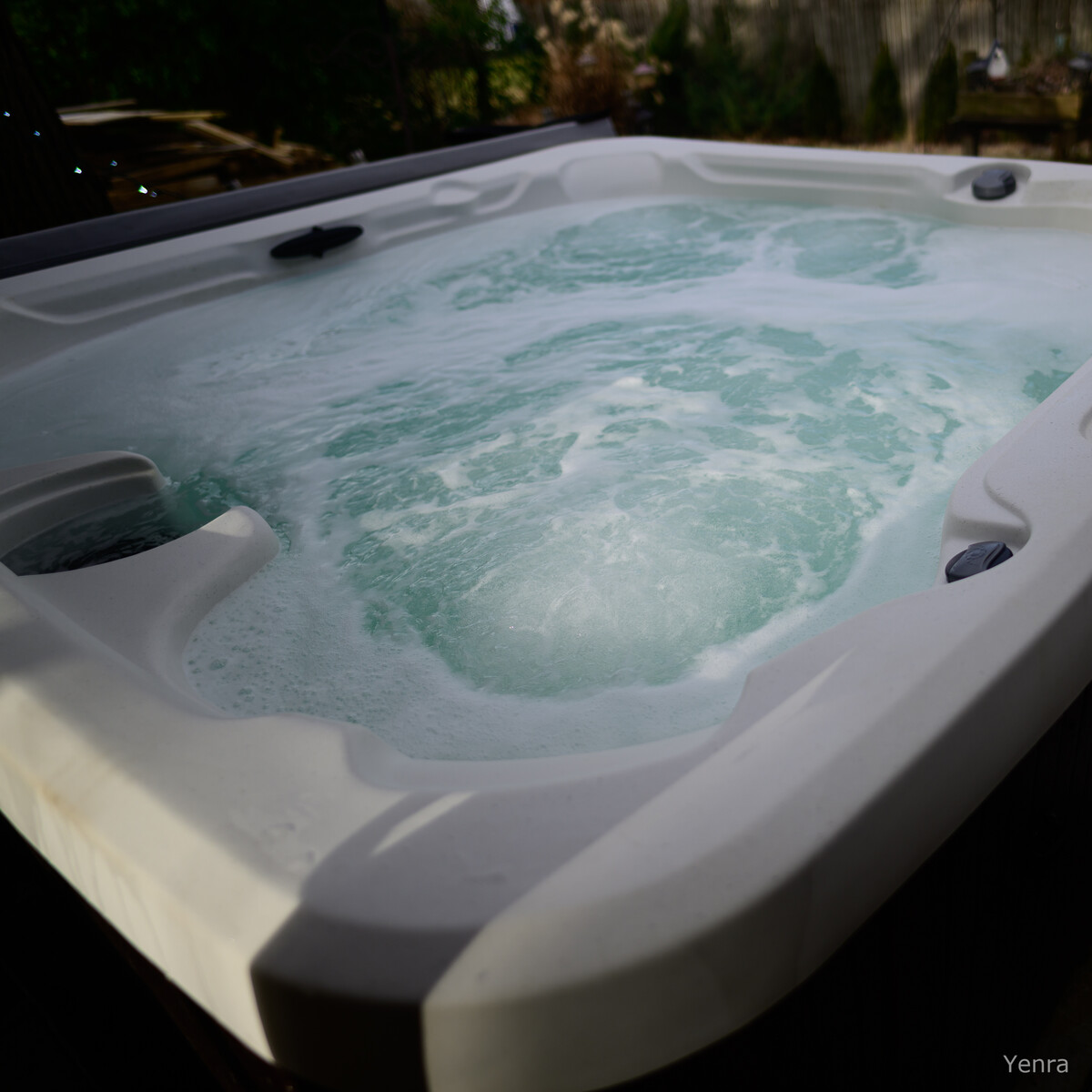 High angle shot of a bubbling white hot tub with swirling water in a backyard setting