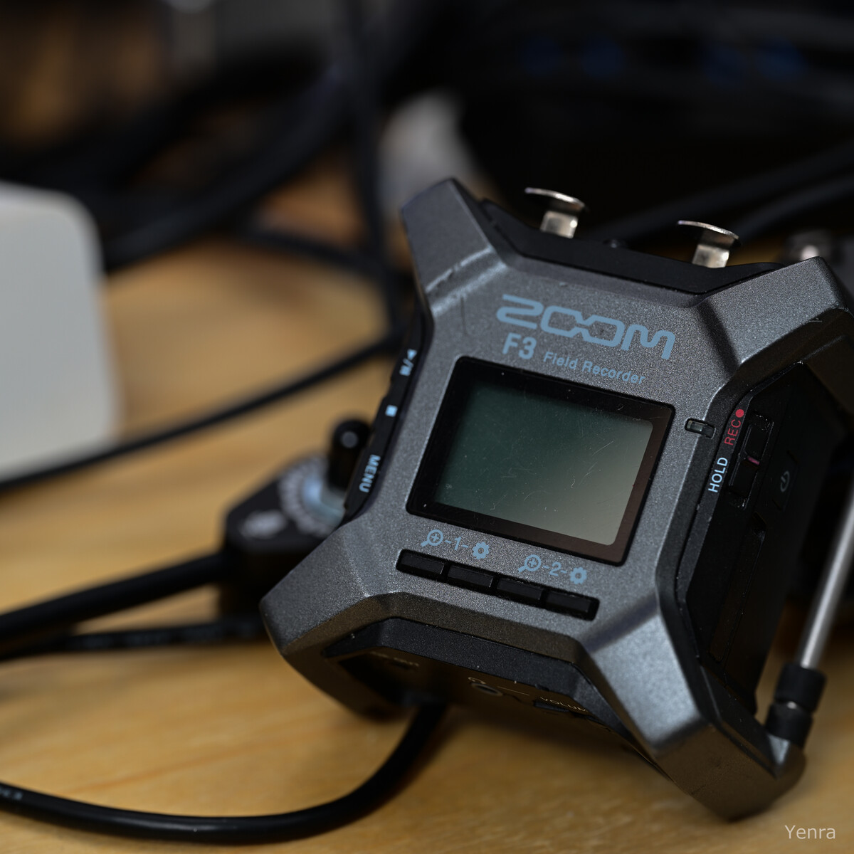 Close-up of a grey Zoom F3 Field Recorder with visible ports and screen on a wooden desk