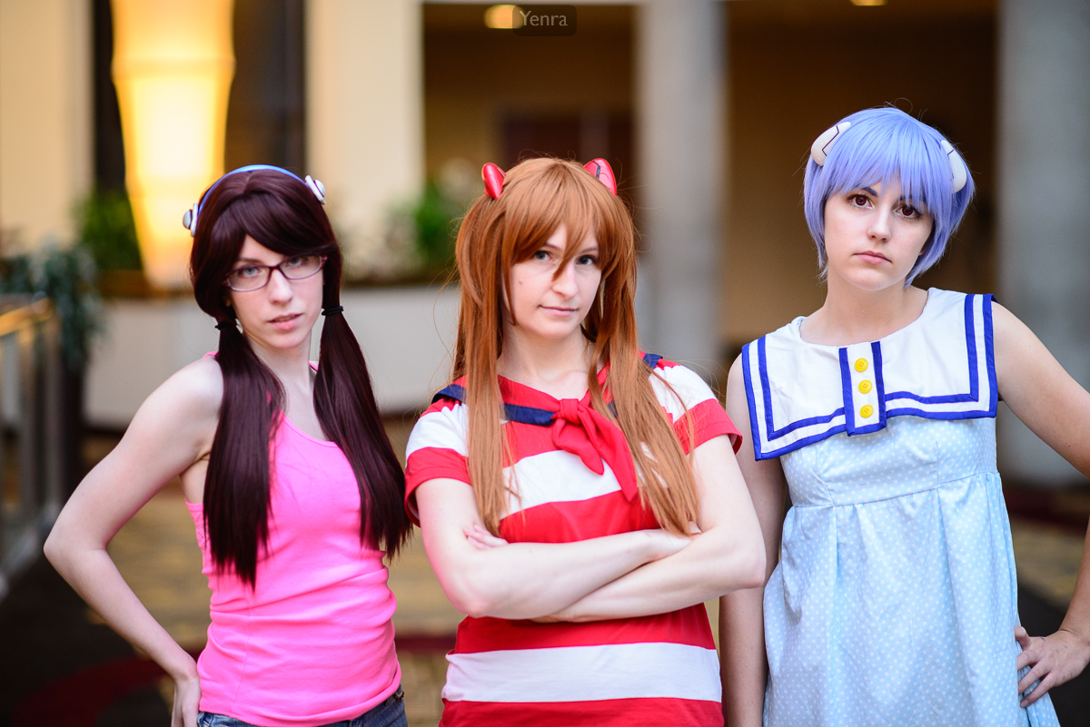 Three women dressed as characters from the anime series Evangelion pose for a photo.